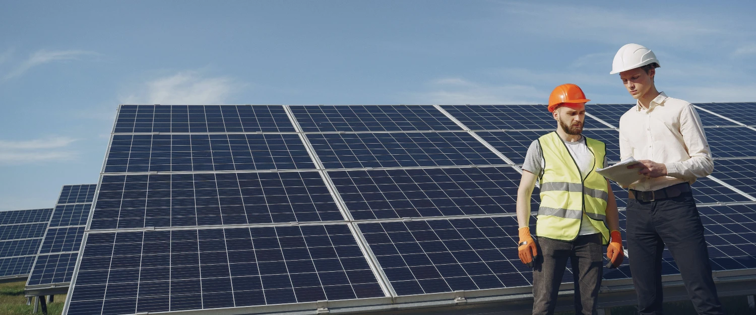 Männer stehen mit einem Bauplan vor Photovoltaik-Modulen
